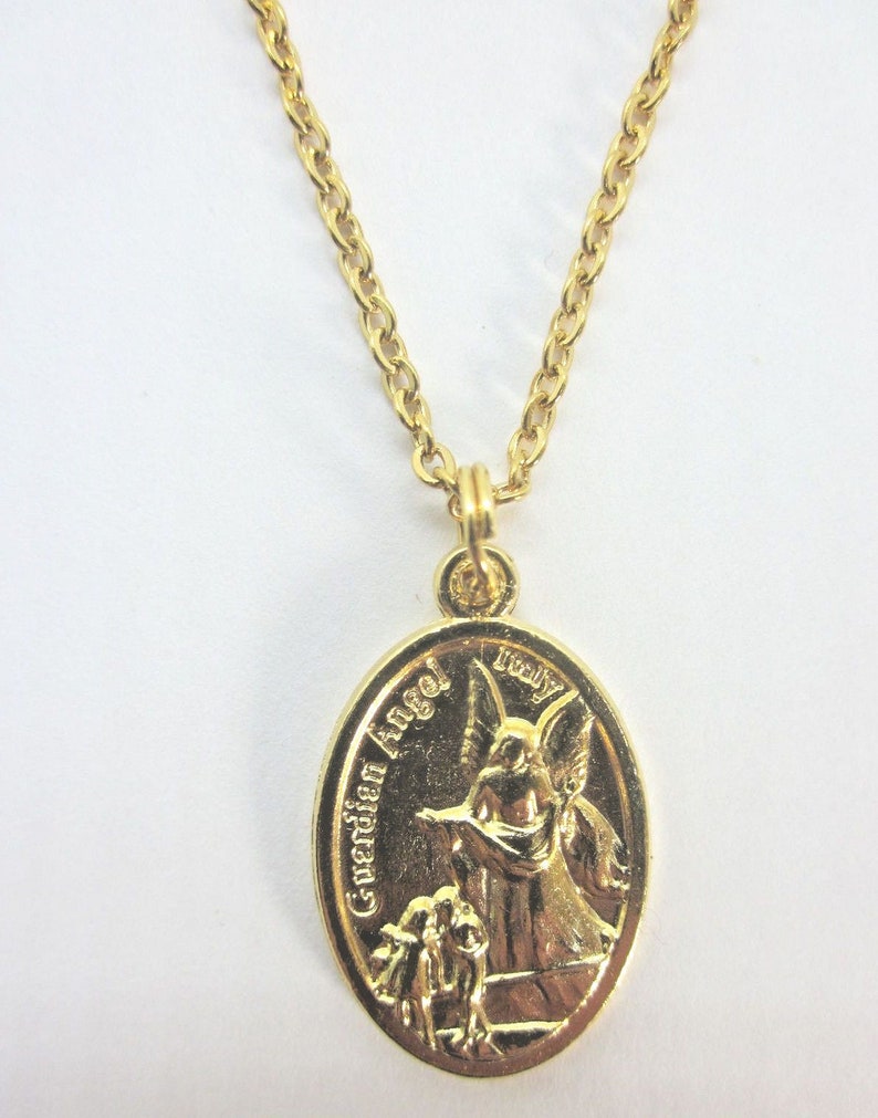 Puede incluir: Collar de cadena dorada con un colgante ovalado dorado que representa a un &aacute;ngel de la guarda con las palabras "Guardian Angel" y "Truly" inscritas en el colgante.