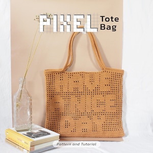 May include: A tan crochet tote bag with the words "PIXEL" and "Tote Bag" in black text. The bag has two handles and a pixelated design. The words "Pattern and Tutorial" are at the bottom of the image.