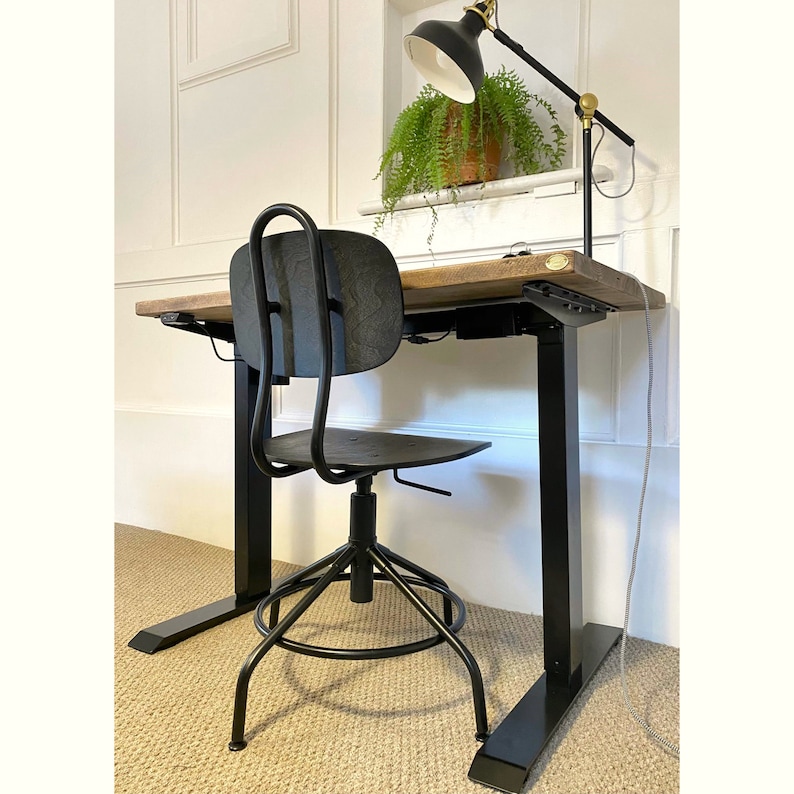 May include: Black adjustable standing desk with a wooden top and a black office chair with a black metal base.