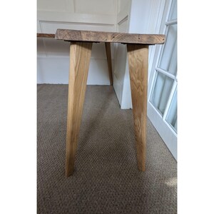 May include: A wooden table with a natural wood finish and four legs. The table is made of reclaimed wood and has a rustic look.