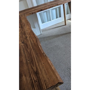 May include: A dark brown wooden L-shaped desk with a natural wood grain finish. The desk has a rustic, farmhouse style.