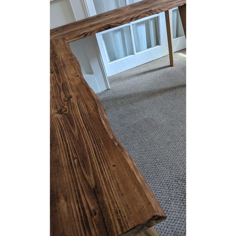 May include: A dark brown wooden L-shaped desk with a natural wood grain finish. The desk has a rustic, farmhouse style.