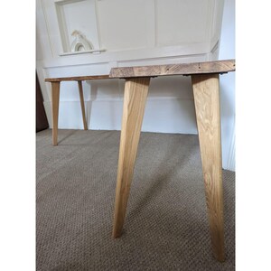 May include: Two wooden tables with a natural wood finish and tapered legs. The tables are made of reclaimed wood and have a rustic look.