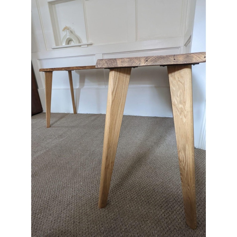 May include: Two wooden tables with a natural wood finish and tapered legs. The tables are made of reclaimed wood and have a rustic look.