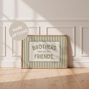 Może przedstawiać: Oprawiony wydruk z napisem "BROTHERS MAKE THE BEST FRIENDS." Grafika przedstawia pasiasty wzór w odcieniach zieleni i bieli, z drewnianą ramą. Wydruk jest eksponowany na drewnianej podłodze na tle białej ściany.
