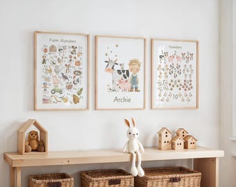 May include: Three framed prints with a farm theme hang on a white wall. The prints feature the alphabet, numbers, and a farm scene with a boy and animals. A wooden shelf below holds a teddy bear, a stuffed bunny, and wooden houses.