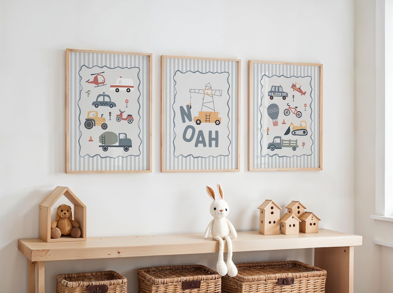 May include: Three framed wall art prints featuring illustrations of construction vehicles, cars, and a crane with the name NOAH in light wood frames. The prints have a gray and white striped background with a scalloped border around the graphics.