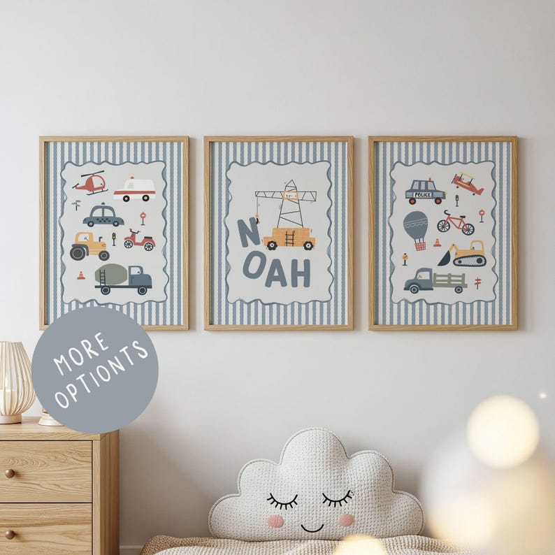 May include: Three framed wall art prints featuring light blue and white vertical stripes. The prints display illustrations of various vehicles including a helicopter, ambulance, crane, police car, and construction trucks, with the name NOAH in the center.