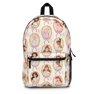 May include: White backpack featuring a repeating pattern of princess portraits in gold frames with pink bows and stars. The backpack has a black top handle, black zippers, and a side mesh pocket.
