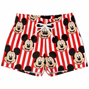 May include: Red and white striped shorts featuring a repeating pattern of Mickey Mouse faces. The shorts have a white drawstring and are designed for casual wear. The overall design is bright and playful.