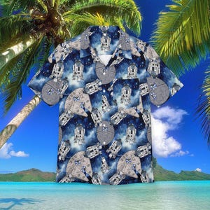 May include: Short-sleeved button-down shirt with a repeating pattern of Star Wars characters and space scenes. The shirt features a blue background with images of R2-D2, the Death Star, and other iconic elements.