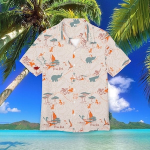 Può includere: Camicia beige con bottoni e stampa safari tropicale. Il design include elefanti, alberi, uccelli e il testo "Pride Rock" e "Circle of Life" in arancione e verde acqua. La camicia ha maniche corte e colletto classico.