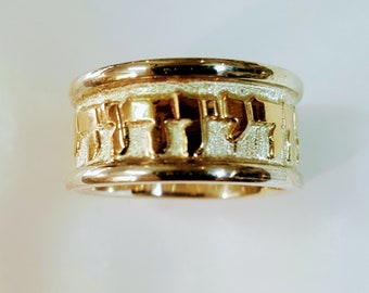 May include: A gold and silver ring with Hebrew lettering around the band.