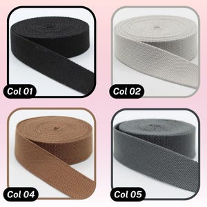 May include: Four spools of woven webbing in various colors: black (Col 01), gray (Col 02), brown (Col 04), and dark gray (Col 05). Each spool is neatly rolled, with a portion of the webbing unrolled to show the texture. The text "Col" followed by a number is visible.