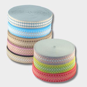 May include: A stack of colourful elastic trim with a geometric pattern. The trim is made of a soft, stretchy material and is perfect for adding a touch of colour and style to any project.