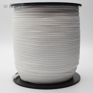 May include: A white spool of cord or rope. The cord is wound tightly around the spool. The spool is made of black plastic.