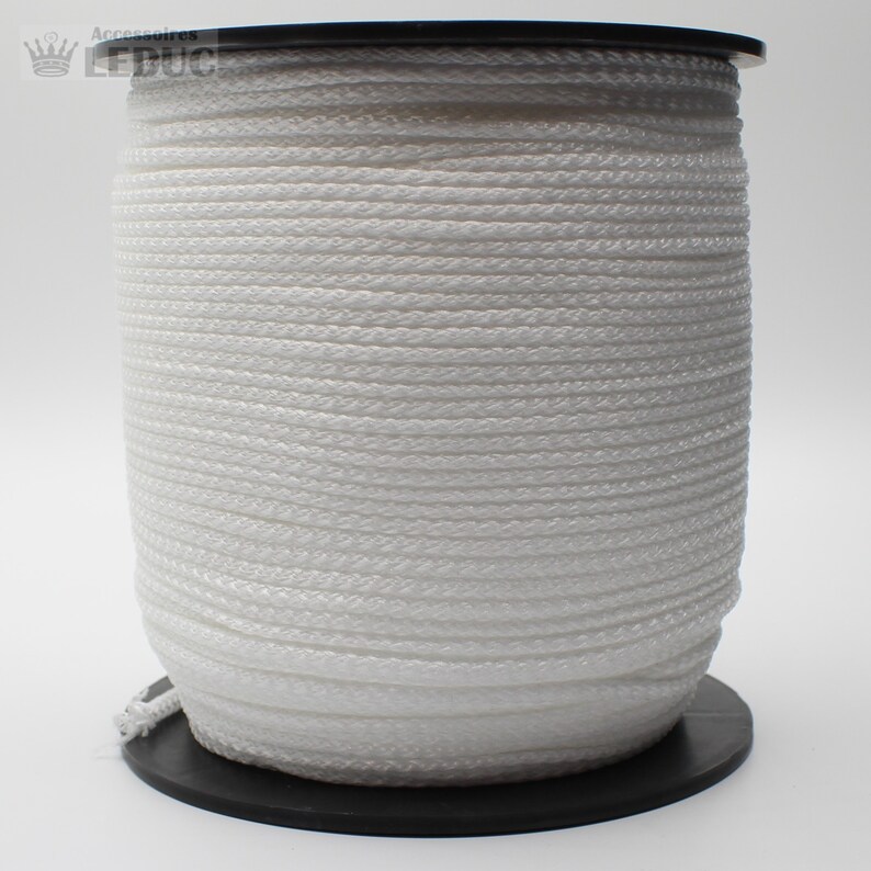 May include: A white spool of cord or rope. The cord is wound tightly around the spool. The spool is made of black plastic.
