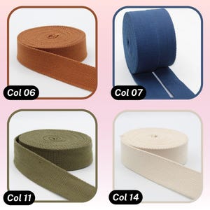 May include: Four spools of canvas webbing in various colors: brown (Col 06), navy blue (Col 07), olive green (Col 11), and off-white (Col 14). Each spool is labeled with its color code. The webbing is tightly rolled and ready for use.