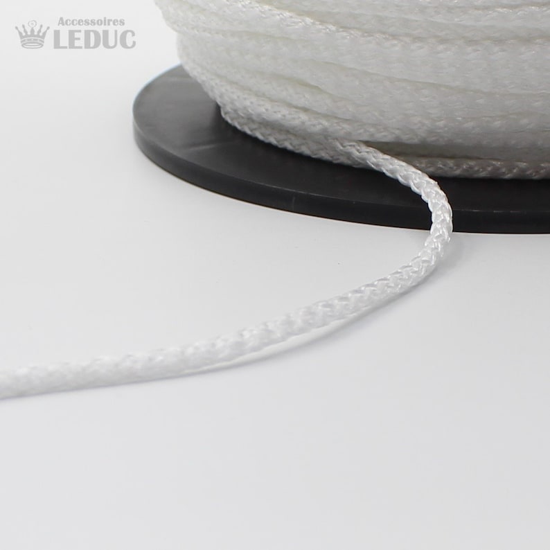 May include: A close-up of a white braided cord, wound around a black spool. The cord is smooth and appears to be made of a synthetic material.
