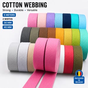 Peut inclure: Rouleaux de sangle en coton de différentes couleurs, dont rose, bleu et vert. Le texte sur l'image indique "COTTON WEBBING" et "Strong, Durable, Versatile." La sangle est disponible en largeurs de 30 mm et 40 mm, et mesure 5 mètres de long.