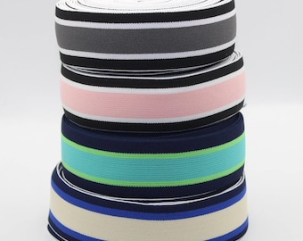 May include: Four rolls of striped elastic trim in different color combinations. The top roll is black and gray, the second is black and pink, the third is navy blue, green, and turquoise, and the bottom roll is navy blue and beige.