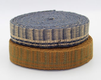 Könnte beinhalten: Zwei Rollen gewebtes Band, eine in Blau und Beige, die andere in Braun und Grün.