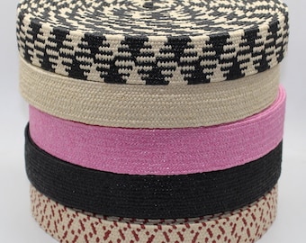 May include: A stack of five different types of woven trim, including black and white, beige, pink, black, and red and beige.