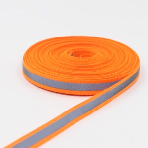 May include: A roll of bright orange reflective ribbon with a gray reflective stripe down the center. The ribbon is coiled, with a portion unrolled, showing the reflective stripe. The ribbon is on a white background.