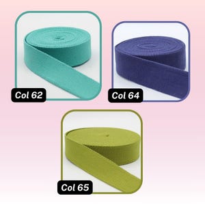 May include: Three spools of fabric ribbon in teal, navy blue, and olive green. Each spool is labeled with a color code: Col 62, Col 64, and Col 65. The ribbon is tightly wound and has a textured appearance.