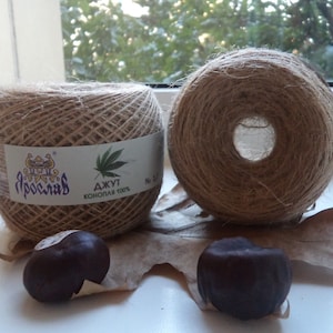 May include: Two spools of natural brown hemp twine, labeled "ДЖУТ КОНОПЛЯ 100%" and "Ярославль". The spools are sitting on a brown leaf with several brown chestnuts.