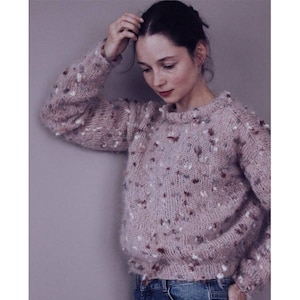 May include: A soft, pink sweater with a speckled pattern. The sweater has a crew neck and long sleeves.