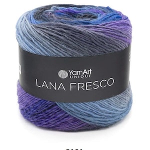 May include: A cylindrical skein of YarnArt UNIQUE LANA FRESCO yarn. The yarn is a blend of blues, purples, and grays. The label is black with white text and the number 8101 is at the bottom.