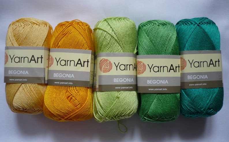 May include: Five skeins of YarnArt Begonia yarn in yellow, orange, green, lime green, and teal green. The yarn is labeled with the brand name and the color name.