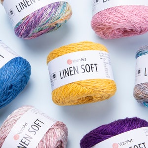 Puede incluir: Surtido de ovillos de hilo en varios colores, incluyendo rosa, azul, amarillo, morado y multicolor. El hilo está etiquetado como "YarnArt Linen Soft" e incluye detalles sobre el contenido y la longitud del hilo.