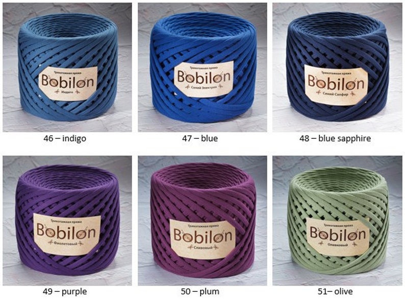 K&ouml;nnte beinhalten: Sechs Spulen aus Baumwollseil in verschiedenen Farben, darunter Indigo, Blau, Saphir, Lila, Pflaume und Oliv. Jede Spule tr&auml;gt ein Etikett mit der Aufschrift "Bobilon".