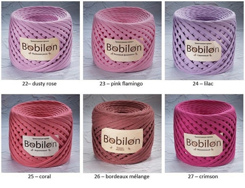K&ouml;nnte beinhalten: Nahaufnahme von sieben Spulen Baumwollseil in verschiedenen Rosat&ouml;nen, Rot und Lila. Die Spulen sind mit dem Markennamen "Bobilon" und dem Farbnamen beschriftet. Die Farben sind Dusty Rose, Pink Flamingo, Lilac, Coral, Bordeaux M&eacute;lange und Crimson.