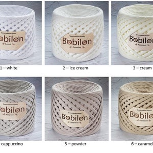 K&ouml;nnte beinhalten: Sechs Spulen Bobilon-Garn in verschiedenen Farben: Wei&szlig;, Eiscreme, Creme, Cappuccino, Puder und Karamell. Jede Spule hat ein Etikett mit dem Markennamen und der Farbe.