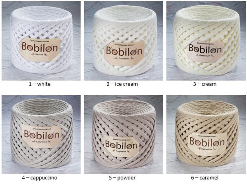 K&ouml;nnte beinhalten: Sechs Spulen Bobilon-Garn in verschiedenen Farben: Wei&szlig;, Eiscreme, Creme, Cappuccino, Puder und Karamell. Jede Spule hat ein Etikett mit dem Markennamen und der Farbe.