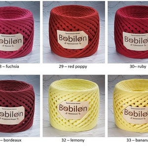 K&ouml;nnte beinhalten: Sechs Spulen mit Baumwollschnur in verschiedenen Farben, darunter Fuchsia, roter Mohn, Rubin, Bordeaux, zitronig und Banane. Jede Spule ist mit "Bobilon" und dem Farbnamen darunter beschriftet.