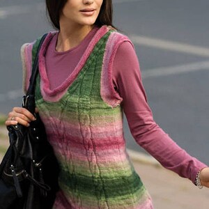 Puede incluir: Una mujer lleva un chaleco de punto a rayas rosa y verde con un dise&ntilde;o de punto de cable. Tambi&eacute;n lleva una camisa rosa de manga larga y lleva un bolso de cuero negro.