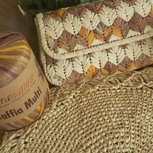 May include: A close-up of a woven clutch bag with a geometric pattern in shades of brown, beige, and orange. The bag is made of natural fibers and has a fringed edge. A ball of raffia yarn in shades of brown, beige, and orange is also visible in the image.