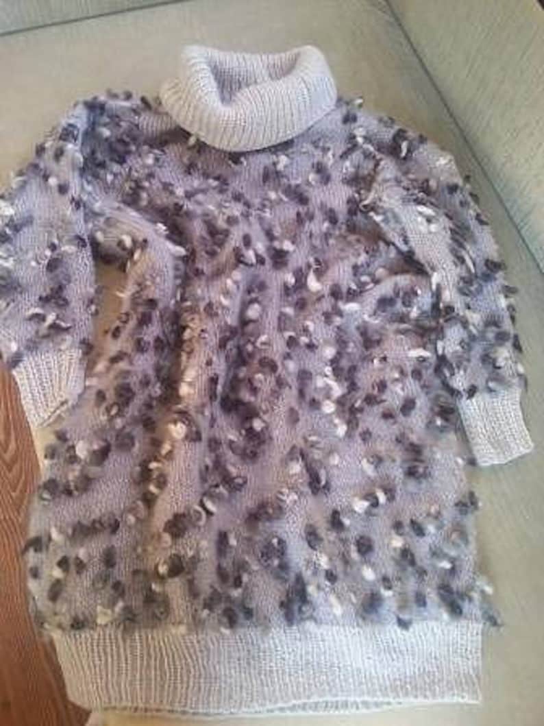 May include: A gray turtleneck sweater with a fuzzy texture and a light gray knit collar.