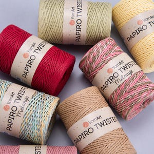以下が含まれることがあります： さまざまな色のYarnArt Paprio Twisted糸巻きの詰め合わせ。赤、黄色、ピンク、ベージュなど、さまざまな色があります。各糸巻きには、ブランド名と製品情報が記載された紙ラベルが付いています。糸はしっかりと巻かれており、天然繊維でできているようです。