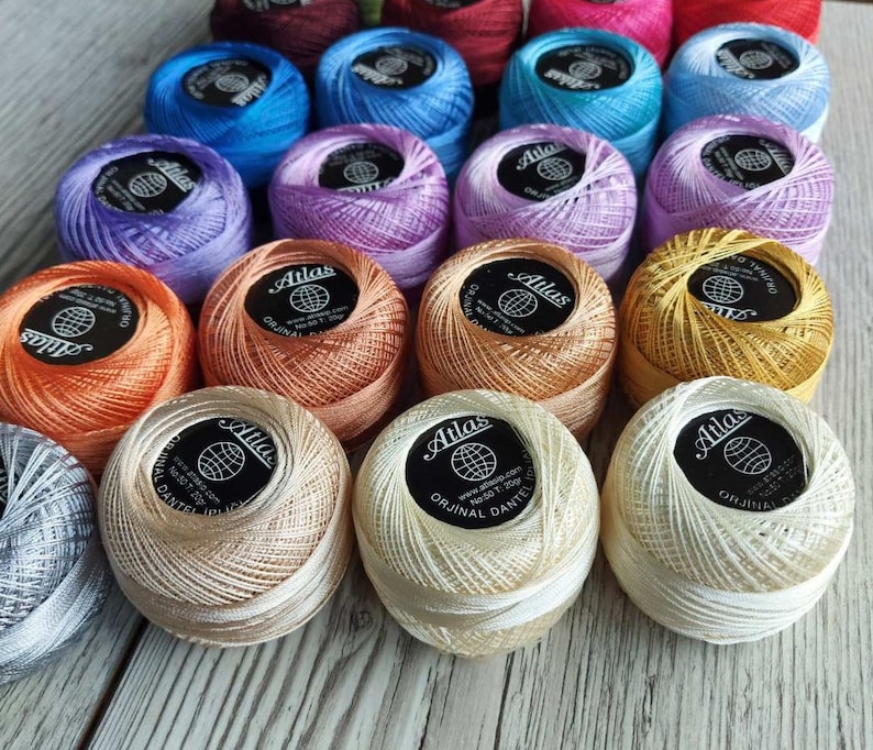 An array of colorful Atlas crochet thread balls neatly arranged on a table.