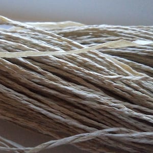 Op de afbeelding: Een close-up van een bundel natuurlijke vezel touw, gemaakt van papier, in een licht beige kleur.