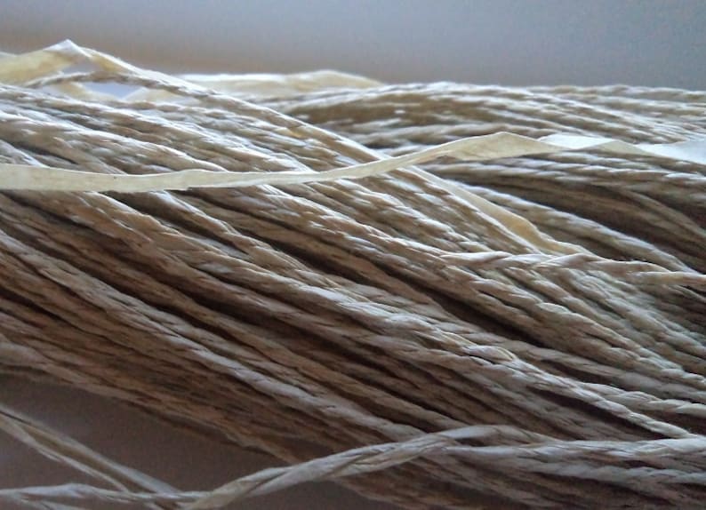 Op de afbeelding: Een close-up van een bundel natuurlijke vezel touw, gemaakt van papier, in een licht beige kleur.