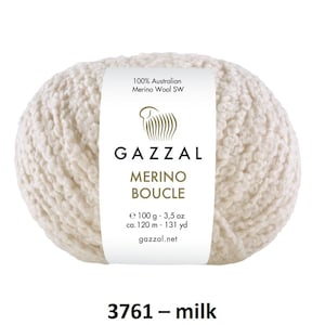Puede incluir: Ovillo de lana Gazzal Merino Boucle blanquecina. La etiqueta dice "100% Australian Merino Wool SW". El ovillo pesa 100 g y tiene unos 120 m de largo. El color es "milk" y el código de producto es 3761.
