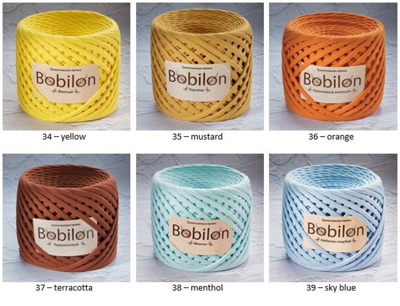 K&ouml;nnte beinhalten: Sechs Spulen Bobilon-Garn in verschiedenen Farben: Gelb, Senf, Orange, Terrakotta, Minze und Himmelblau. Jede Spule tr&auml;gt ein Etikett mit dem Markennamen und dem Farbnamen.