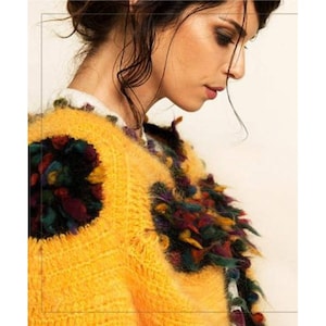 May include: A yellow fuzzy sweater with colorful embroidered details. The sweater has a loose fit and a round neckline.