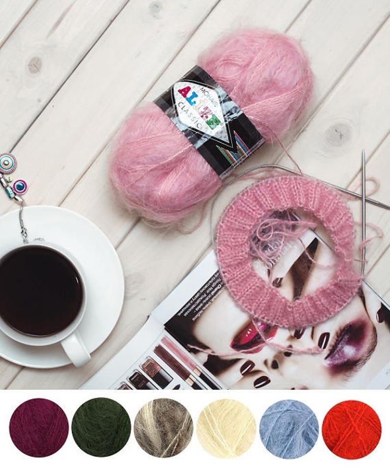May include: A skein of light pink Alize Mohair Classic yarn with a black label, accompanied by a circular knitting needle with pink yarn stitches. Below are six circular swatches of yarn in dark purple, dark green, brown, cream, blue, and red.